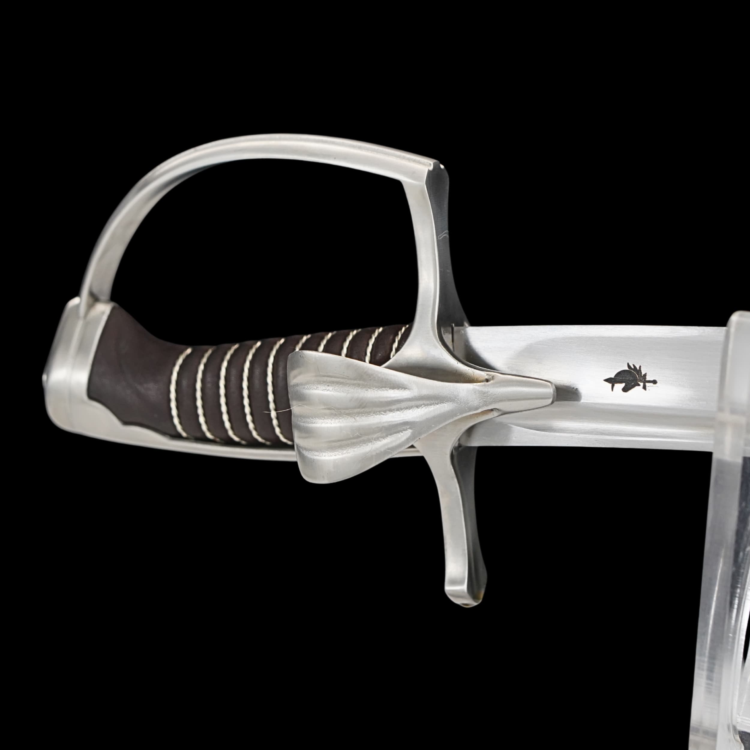 Close-up of a sword with a silver hilt and black grip on a black background