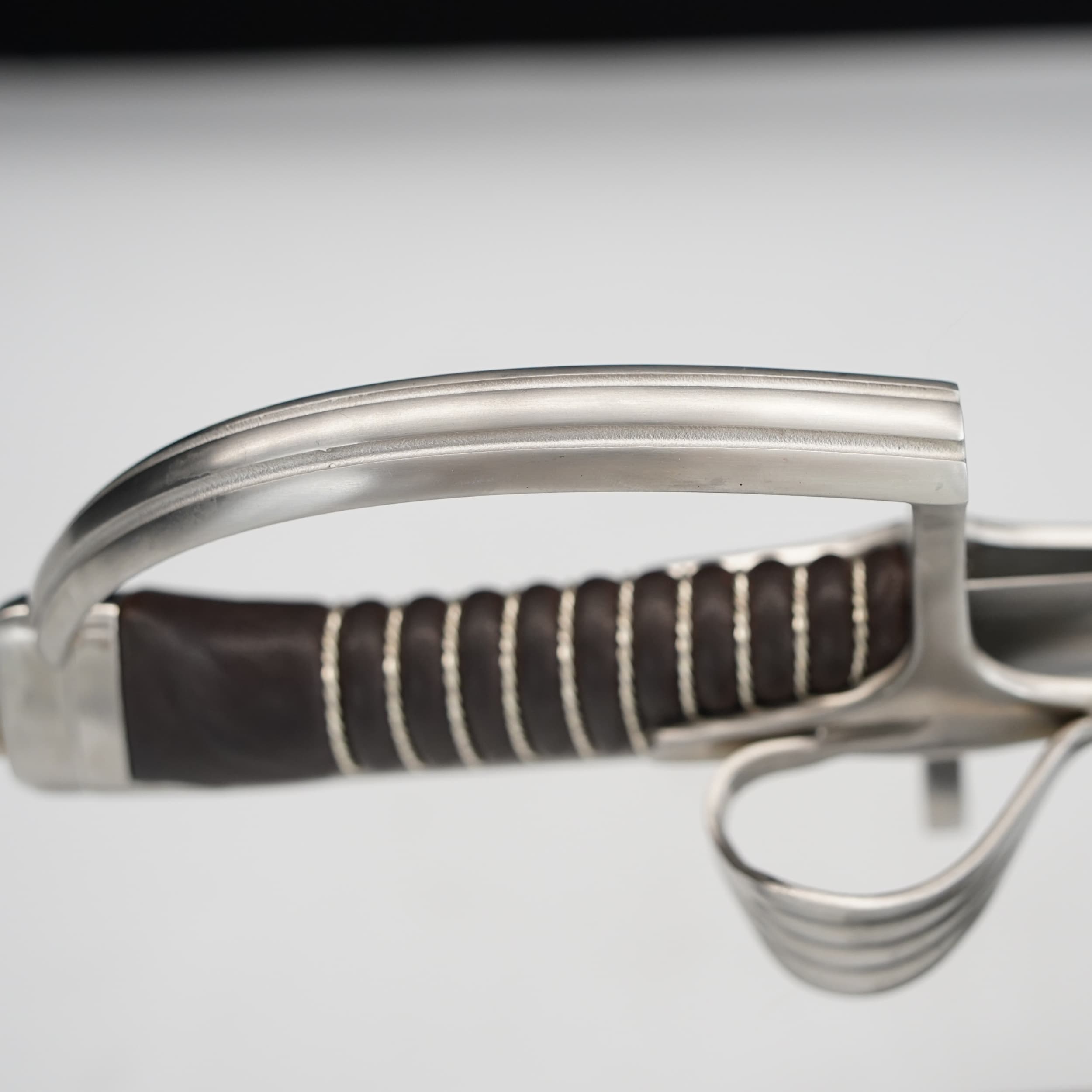Close-up of a sword with a brown handle on a light gray background