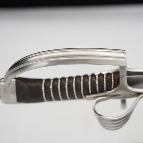 Close-up of a sword with a brown handle on a light gray background
