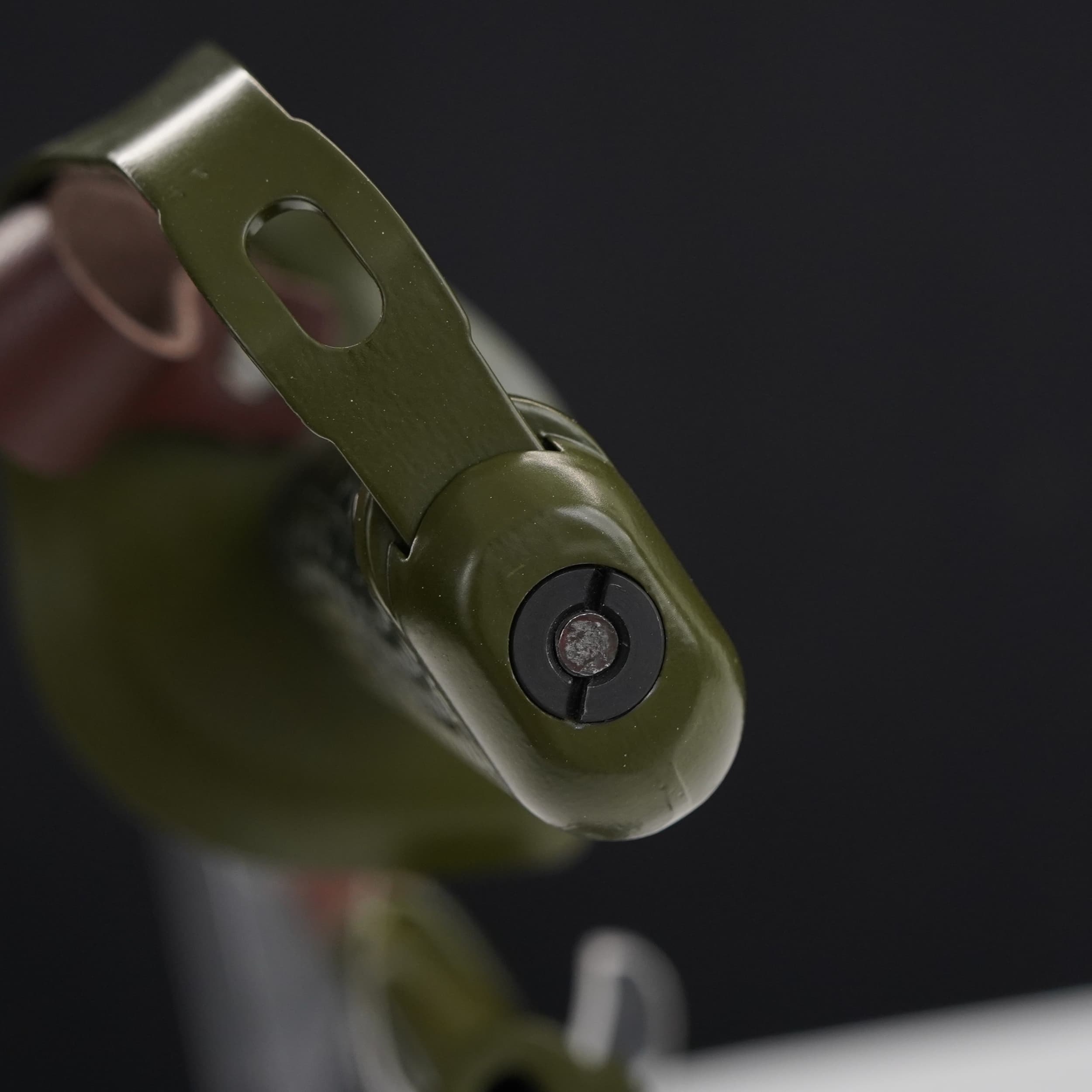 Close-up of a green metal object with a black component on a dark background