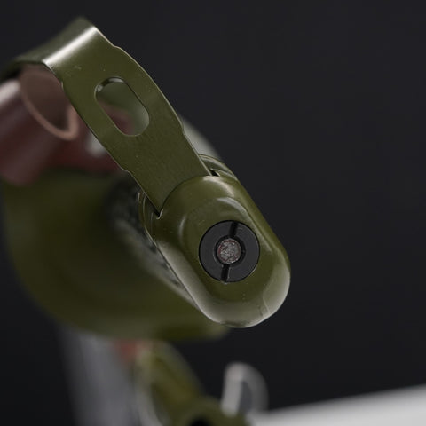Close-up of a green metal object with a black component on a dark background