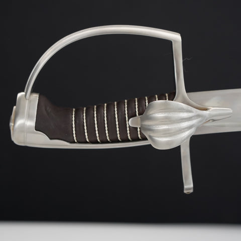 Close-up of a sword with a silver hilt and brown grip on a black background