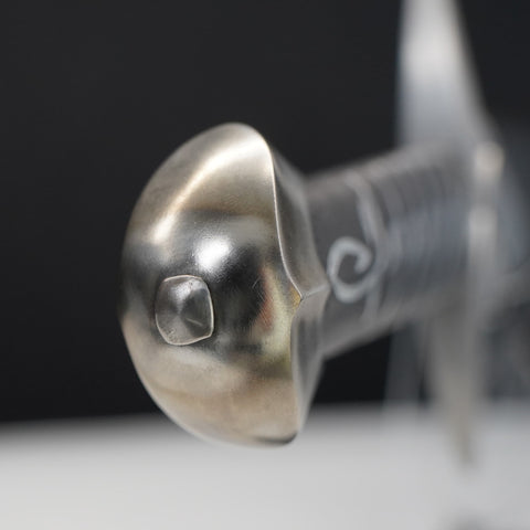 Close-up of a metallic sword hilt with intricate design on a dark background