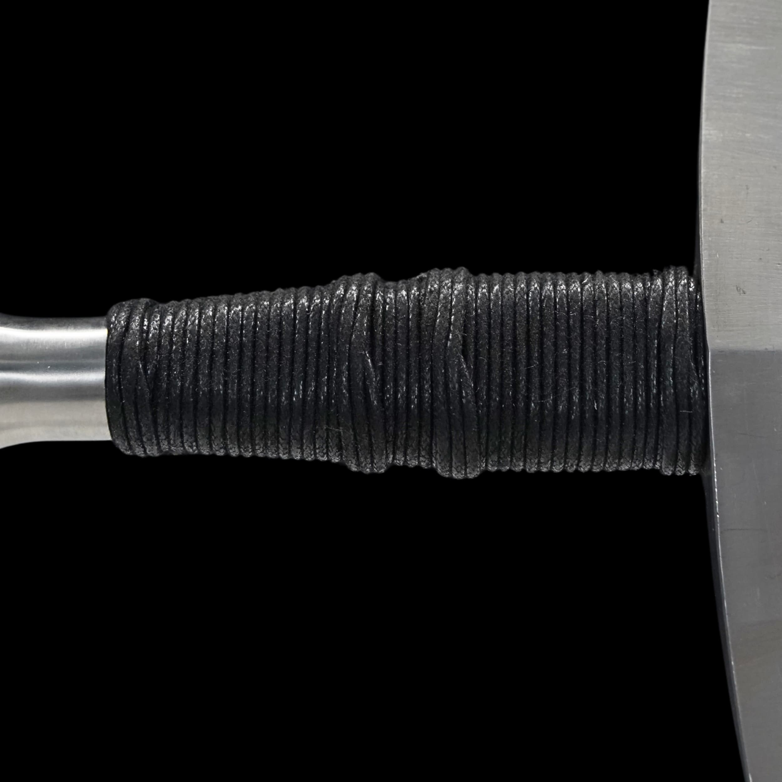 Close-up of a textured black handle on a metal object with a plain background