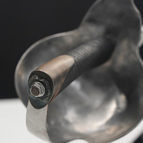 Metal tool with a screw-like component on a black background