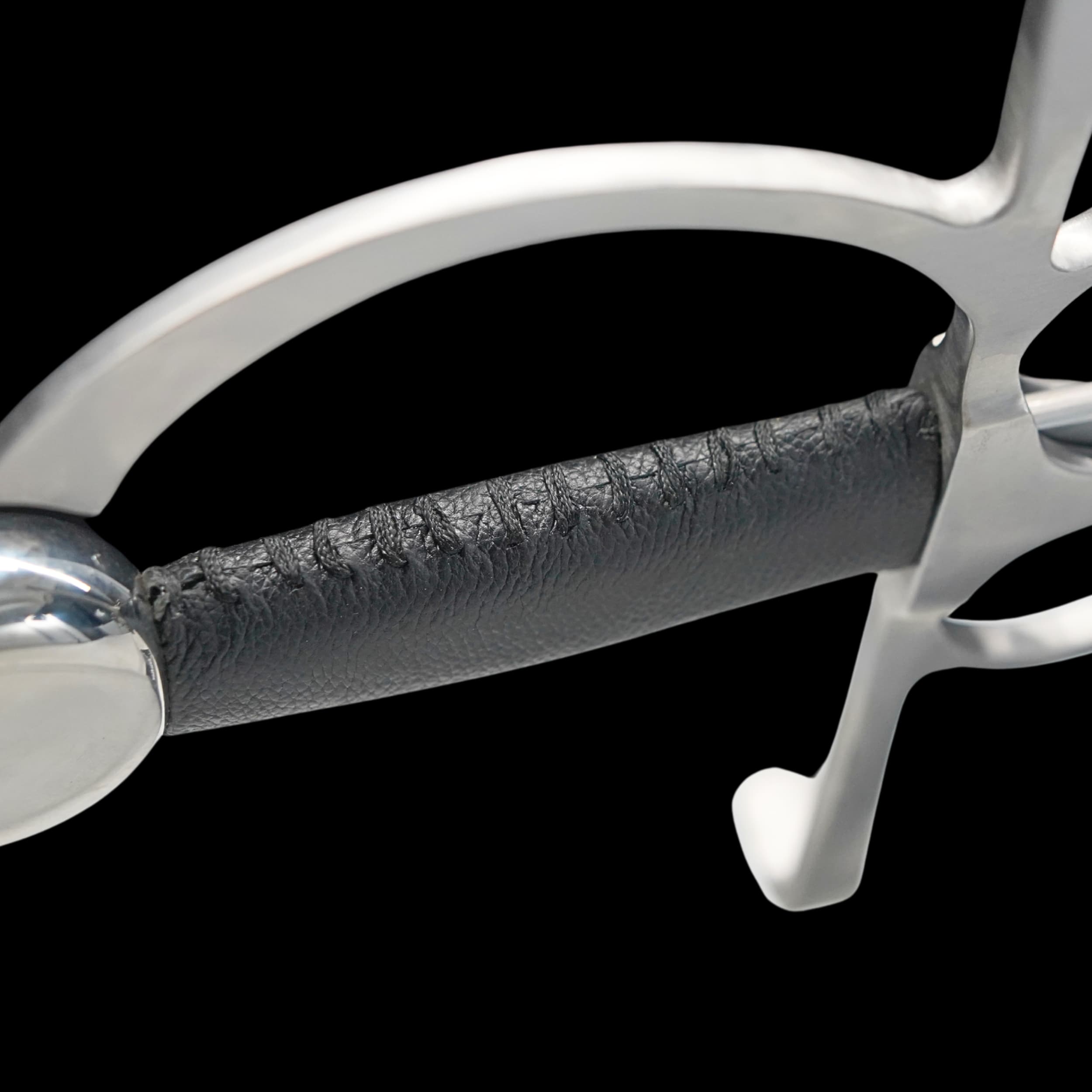 Close-up of a metallic equestrian bit with leather mouthpiece on a black background