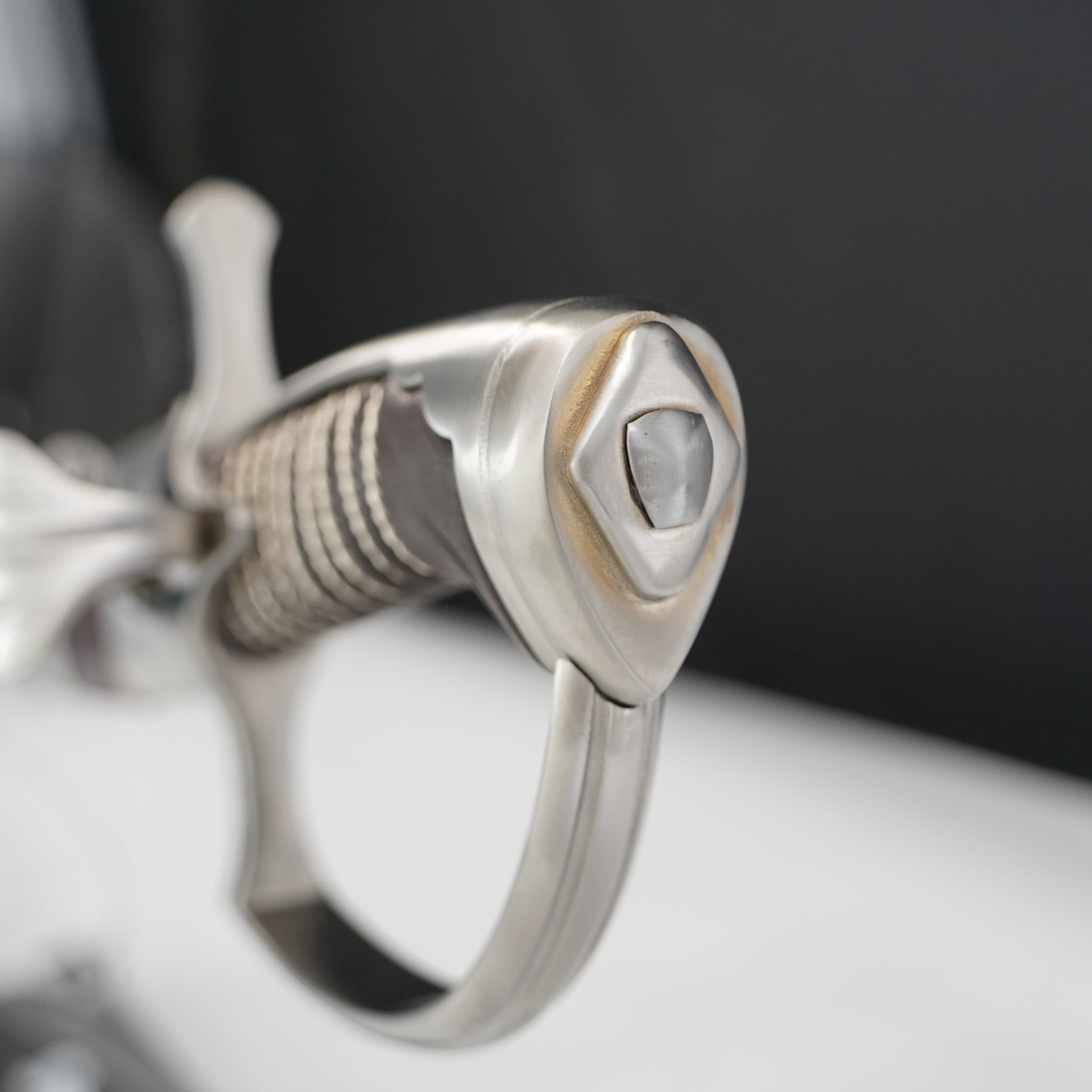 Close-up of a silver ring with intricate design on a dark background