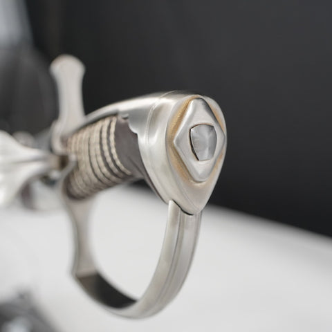 Close-up of a silver ring with intricate design on a dark background