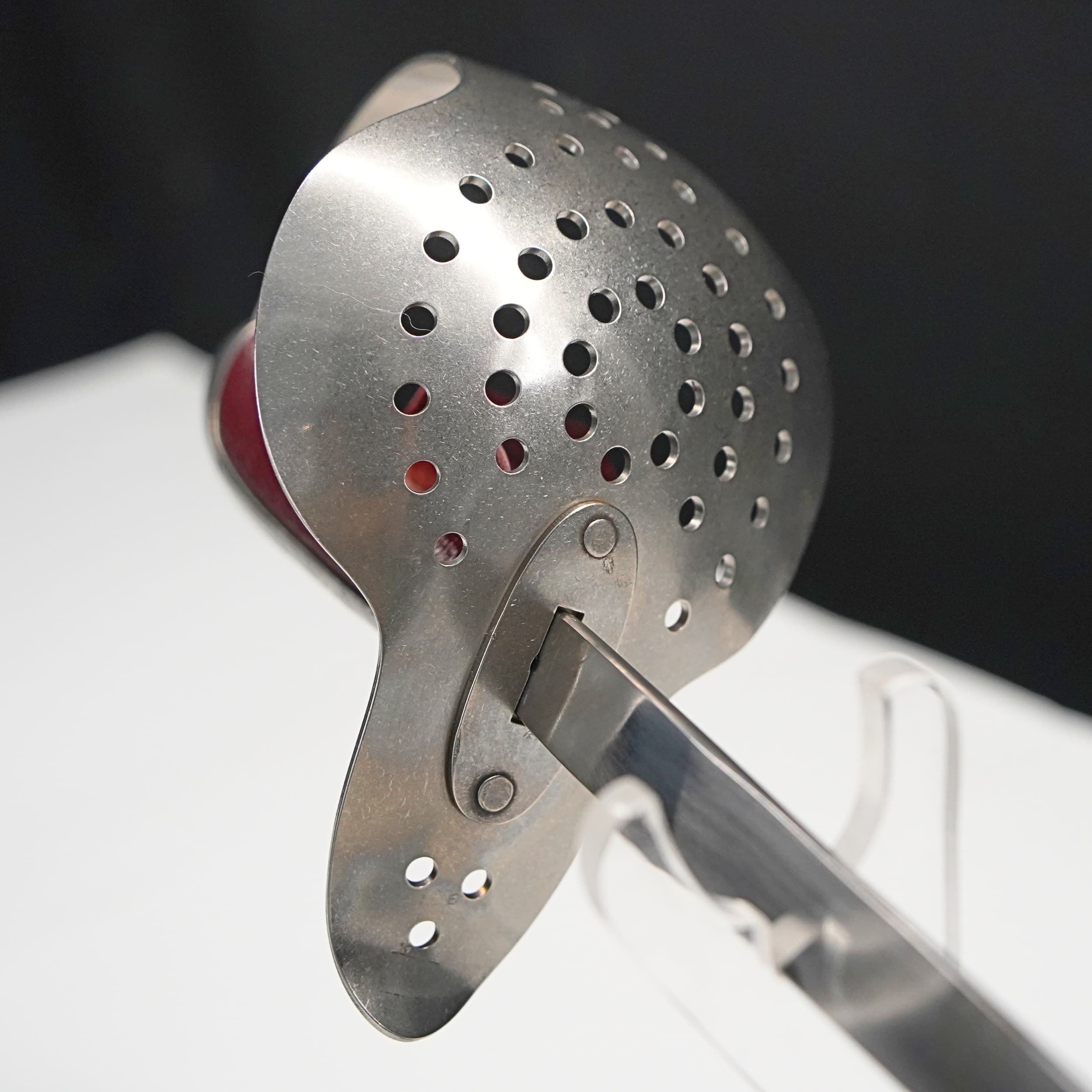 Metallic kitchen tool with perforated design on a white surface