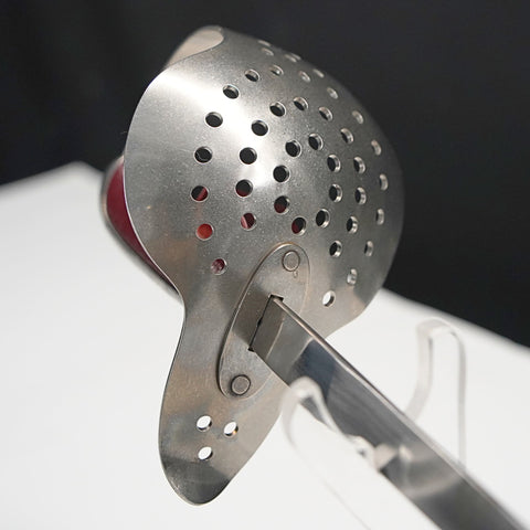 Metallic kitchen tool with perforated design on a white surface