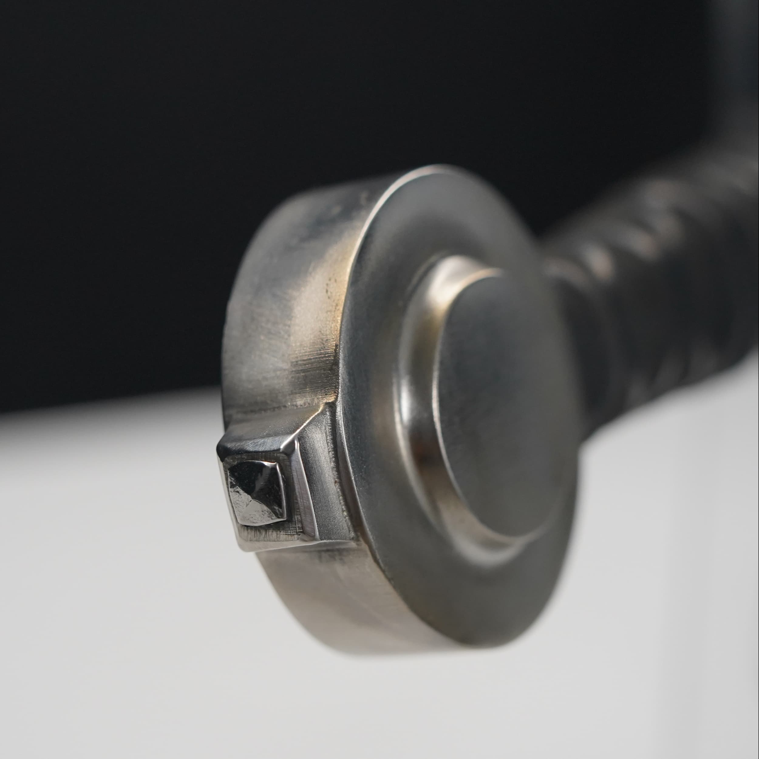 Close-up of a metal screw with a black handle on a white background